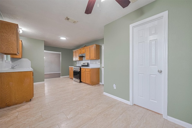 10834 Glenora Dr, Houston, TX 77065 - kitchen featuring stainless steel gas range, under cabinet range hood, a ceiling fan, light countertops, and brown cabinetry