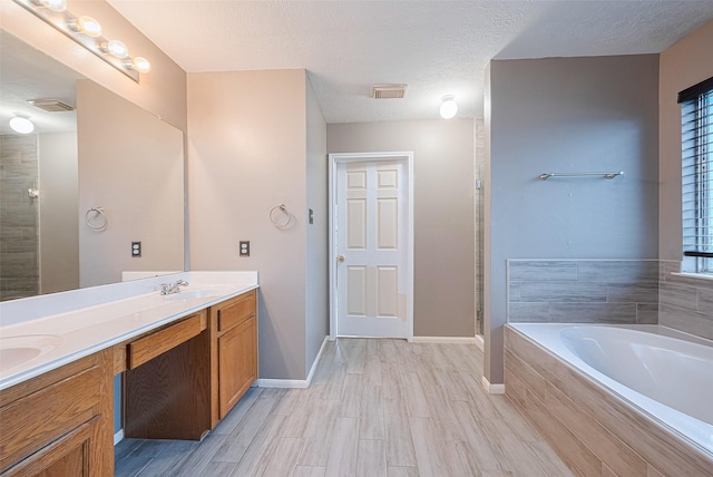 10834 Glenora Dr, Houston, TX 77065 - bathroom with a bath, double vanity, a stall shower, wood finished floors, and a textured ceiling