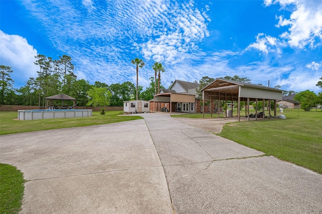view of front of property featuring concrete driveway, a front lawn, an outdoor pool, and a carport