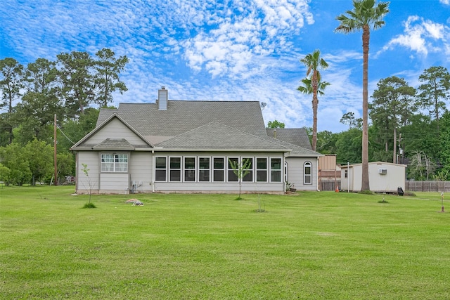 back of house with a lawn, a shingled roof, a chimney, and an outdoor structure