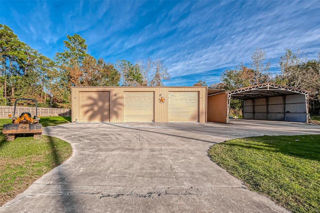 garage with fence, driveway, and a carport