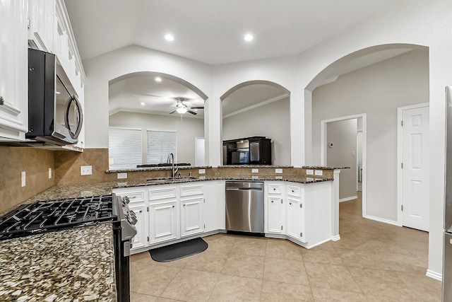 kitchen with a ceiling fan, a sink, backsplash, vaulted ceiling, and stainless steel appliances