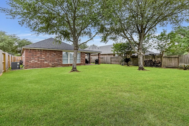 view of yard with a fenced backyard and central AC unit