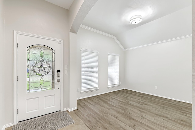 entryway with crown molding, baseboards, vaulted ceiling, and light wood-style flooring
