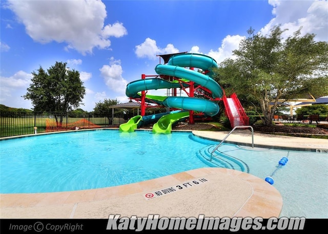 community pool with fence and a water slide