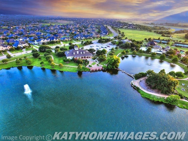 aerial view at dusk featuring a water view and a residential view