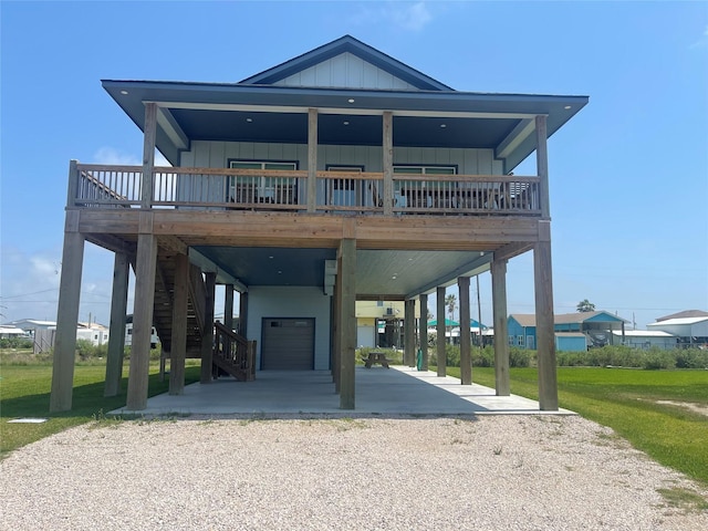 coastal inspired home with board and batten siding, a carport, stairway, gravel driveway, and an attached garage