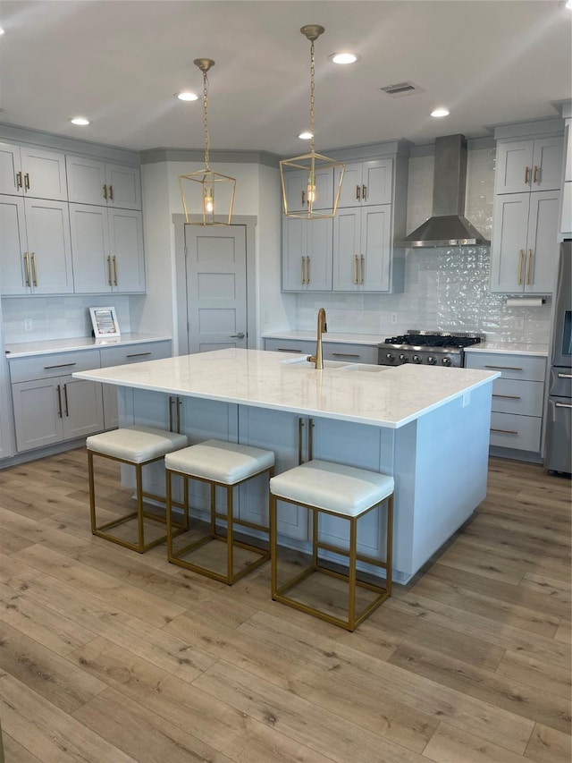 kitchen with wall chimney range hood, gray cabinetry, and visible vents