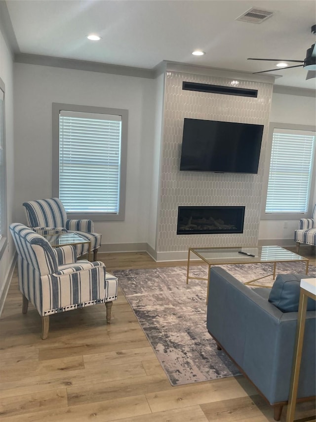 living room with a large fireplace, baseboards, wood finished floors, and visible vents