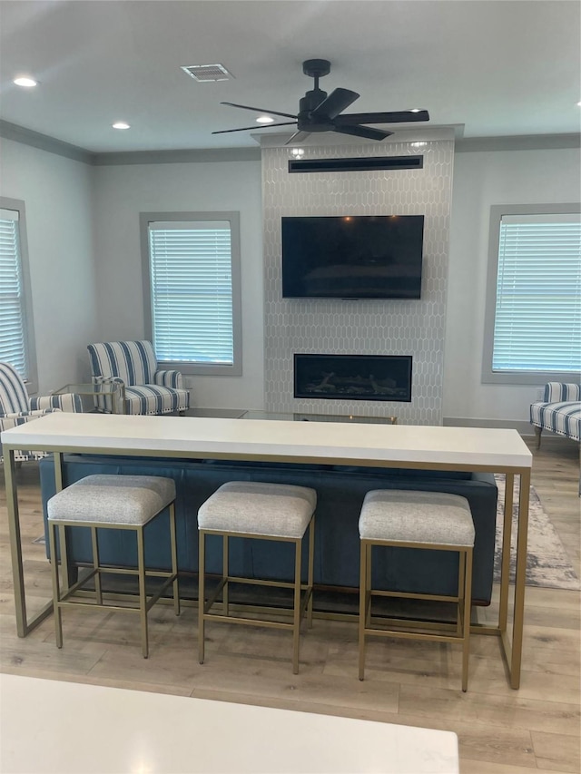 kitchen featuring visible vents, a fireplace, plenty of natural light, light wood-type flooring, and a ceiling fan