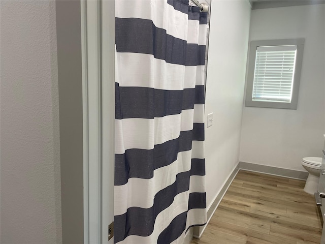 full bathroom featuring toilet, baseboards, wood finished floors, and a shower with curtain