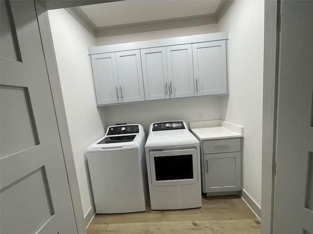 laundry area with cabinet space, crown molding, light wood-style floors, baseboards, and washing machine and dryer