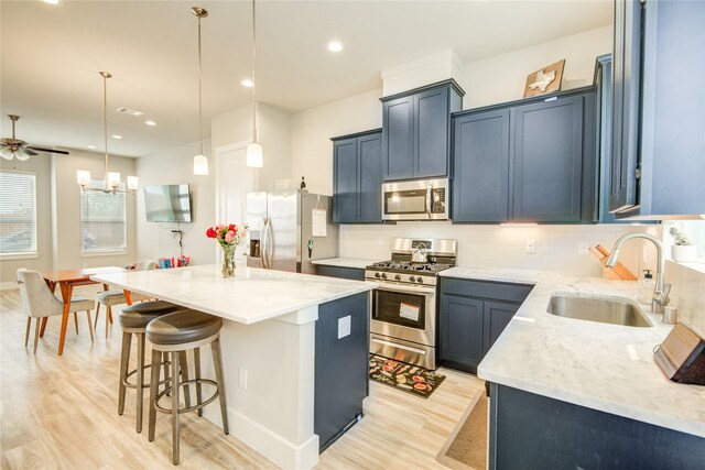7709 Rainbow Close Ln, Houston, TX 77055 - kitchen with appliances with stainless steel finishes, a sink, light wood-style floors, a kitchen breakfast bar, and a center island