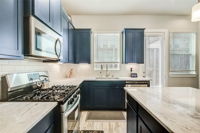 7709 Rainbow Close Ln, Houston, TX 77055 - kitchen with backsplash, appliances with stainless steel finishes, a sink, and light stone counters