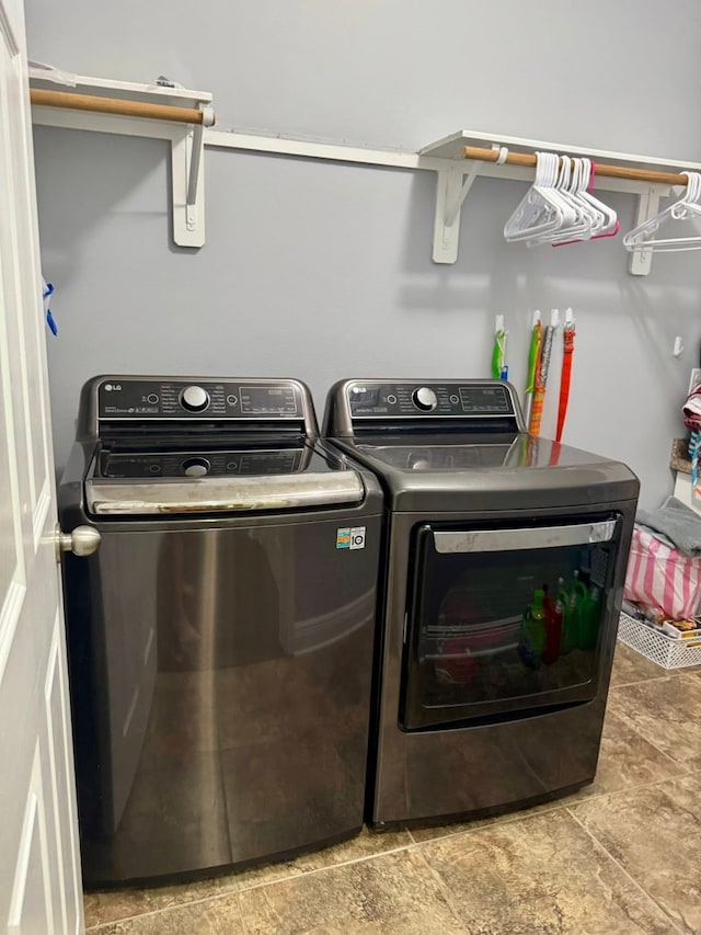 laundry room featuring laundry area, washer and clothes dryer, and stone finish floor