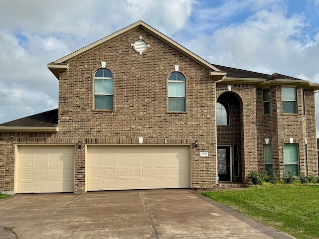 view of front of house featuring brick siding, an attached garage, driveway, and a front yard