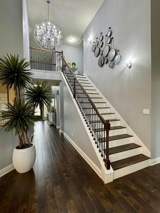 staircase featuring an inviting chandelier, baseboards, and hardwood / wood-style flooring