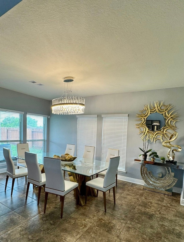 dining space featuring a textured ceiling, visible vents, baseboards, and an inviting chandelier