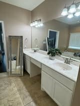 full bath featuring double vanity, a sink, and tile patterned flooring