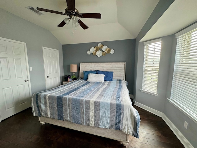 bedroom with ceiling fan, visible vents, baseboards, vaulted ceiling, and hardwood / wood-style flooring