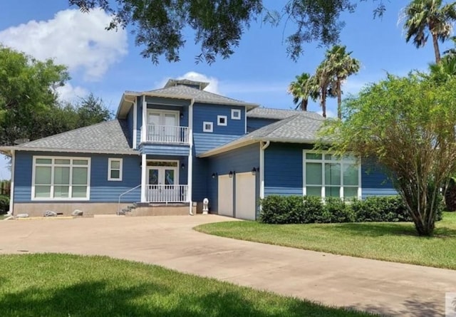 view of front of home featuring a front lawn, a balcony, french doors, concrete driveway, and an attached garage
