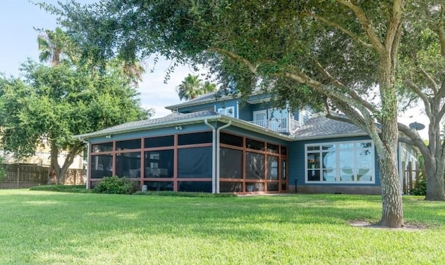 back of property featuring a sunroom, a lawn, fence, and a balcony