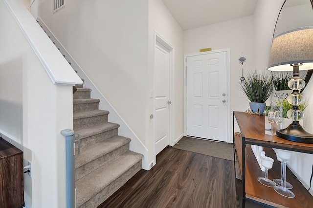entryway with stairway, baseboards, dark wood-style flooring, and visible vents