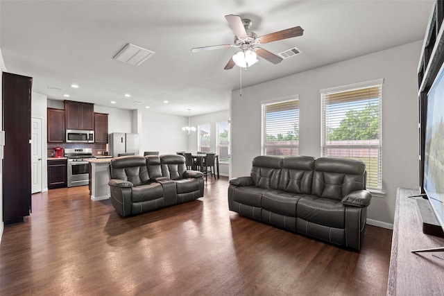 living area featuring visible vents, recessed lighting, dark wood-style flooring, and ceiling fan with notable chandelier