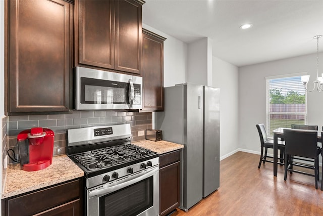 kitchen with backsplash, appliances with stainless steel finishes, dark brown cabinetry, and a chandelier