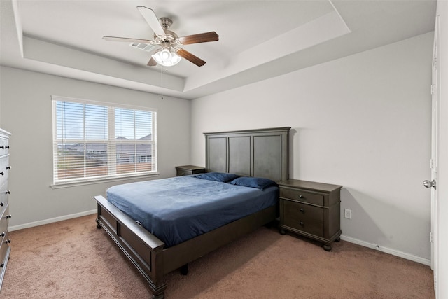 bedroom featuring a ceiling fan, baseboards, light carpet, and a tray ceiling