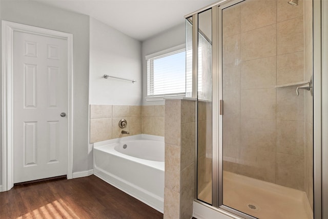 full bathroom featuring a shower stall, a bath, and wood finished floors