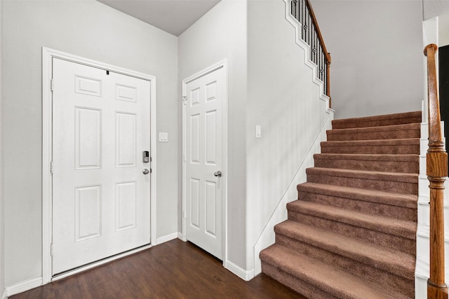 foyer entrance with stairway, baseboards, and dark wood-type flooring