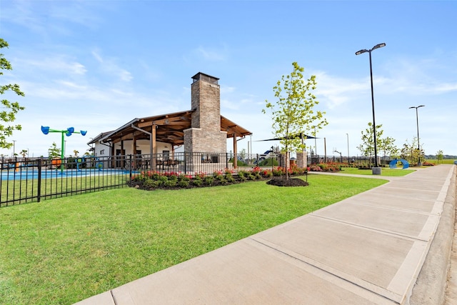 view of community with fence, a pool, a lawn, and a patio