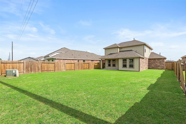 rear view of property featuring a yard, a fenced backyard, and roof with shingles