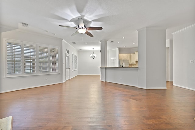 unfurnished living room featuring crown molding, visible vents, ceiling fan with notable chandelier, and hardwood / wood-style floors