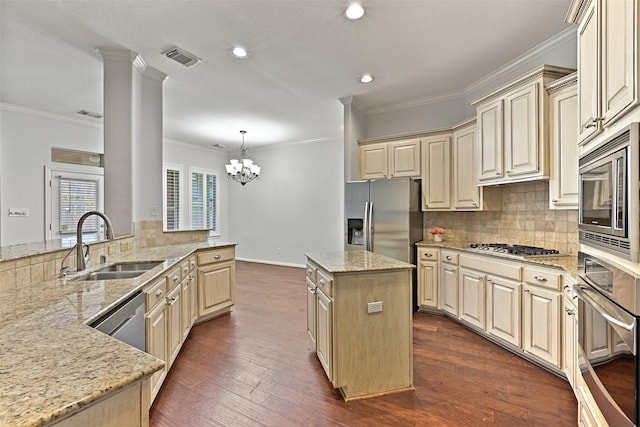 kitchen featuring backsplash, appliances with stainless steel finishes, cream cabinets, a sink, and light stone counters