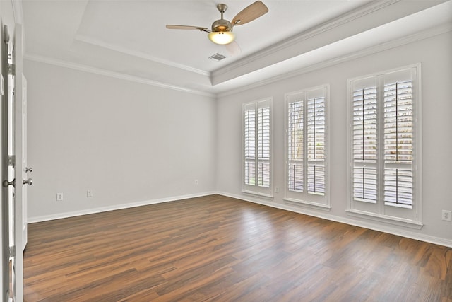 empty room featuring ceiling fan, dark wood-style flooring, visible vents, ornamental molding, and a tray ceiling