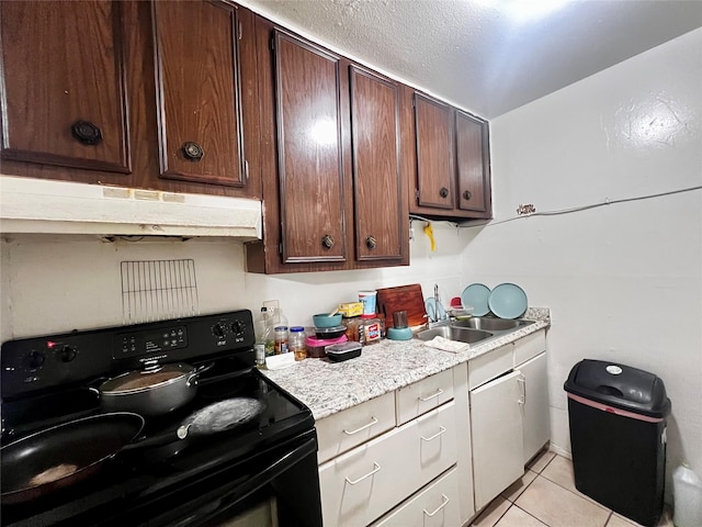 kitchen with a sink, light countertops, light tile patterned floors, black range with electric cooktop, and under cabinet range hood