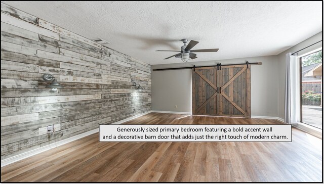 6627 Gleneagles Dr, Pasadena, TX 77505 - empty room with a textured ceiling, visible vents, a barn door, and wood finished floors