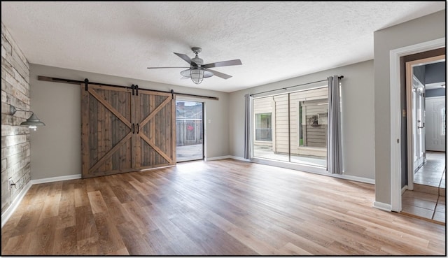 6627 Gleneagles Dr, Pasadena, TX 77505 - empty room featuring a ceiling fan, a textured ceiling, a barn door, and light wood-style floors