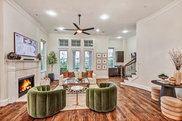 living area with ceiling fan, a fireplace, ornamental molding, and wood finished floors