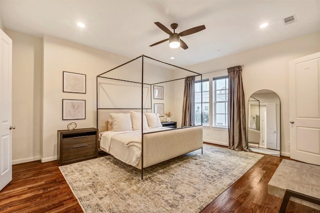 bedroom featuring dark wood-style flooring, visible vents, arched walkways, baseboards, and recessed lighting