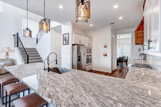 6006 Henry Hamlet Dr, Conroe, TX 77304 - kitchen with appliances with stainless steel finishes, a sink, white cabinets, light stone countertops, and crown molding