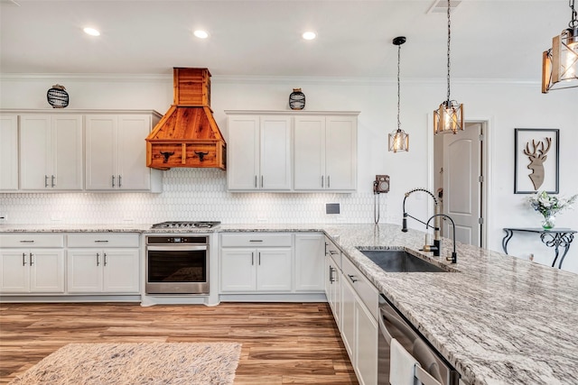 6006 Henry Hamlet Dr, Conroe, TX 77304 - kitchen featuring a sink, appliances with stainless steel finishes, white cabinets, light wood-type flooring, and custom exhaust hood