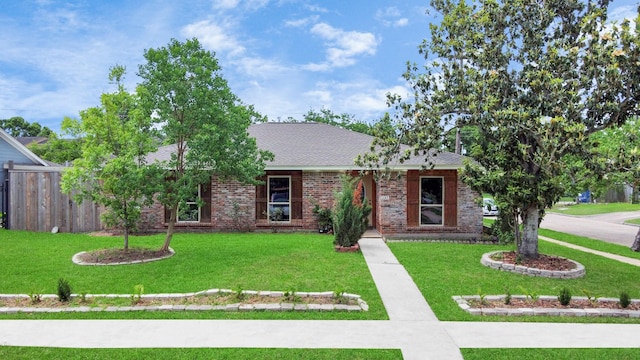 ranch-style house with brick siding, a shingled roof, a front lawn, and fence