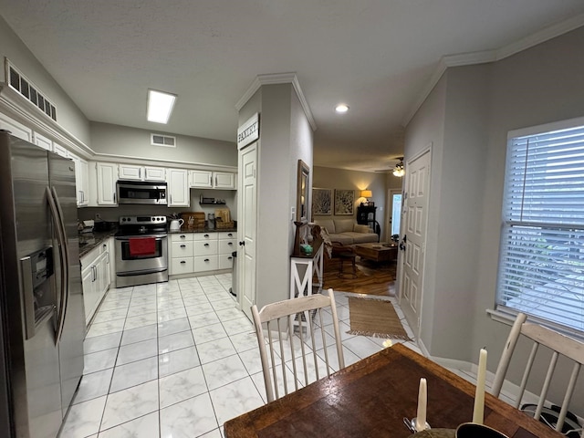 kitchen featuring visible vents, dark countertops, appliances with stainless steel finishes, white cabinets, and open floor plan