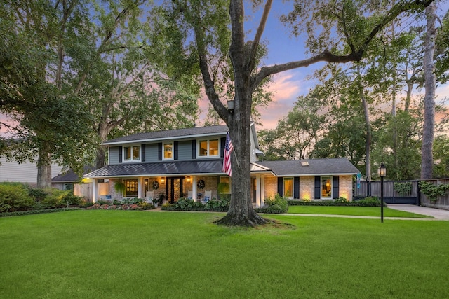 view of front of property with a porch, brick siding, fence, and a front yard