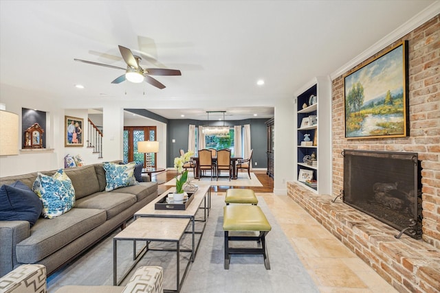 living area featuring a brick fireplace, baseboards, stairway, built in shelves, and a ceiling fan