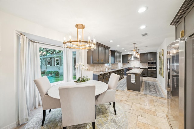 dining room featuring a notable chandelier, recessed lighting, baseboards, visible vents, and stone tile flooring