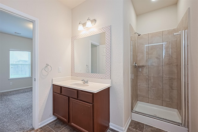 bathroom featuring vanity, tile patterned floors, baseboards, visible vents, and tiled shower